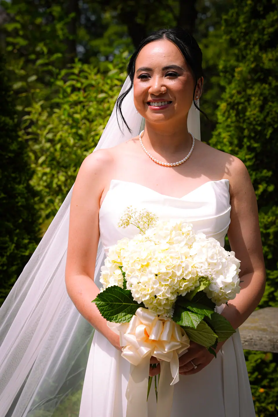 A bride outdoors holding her bouquet in the summer light