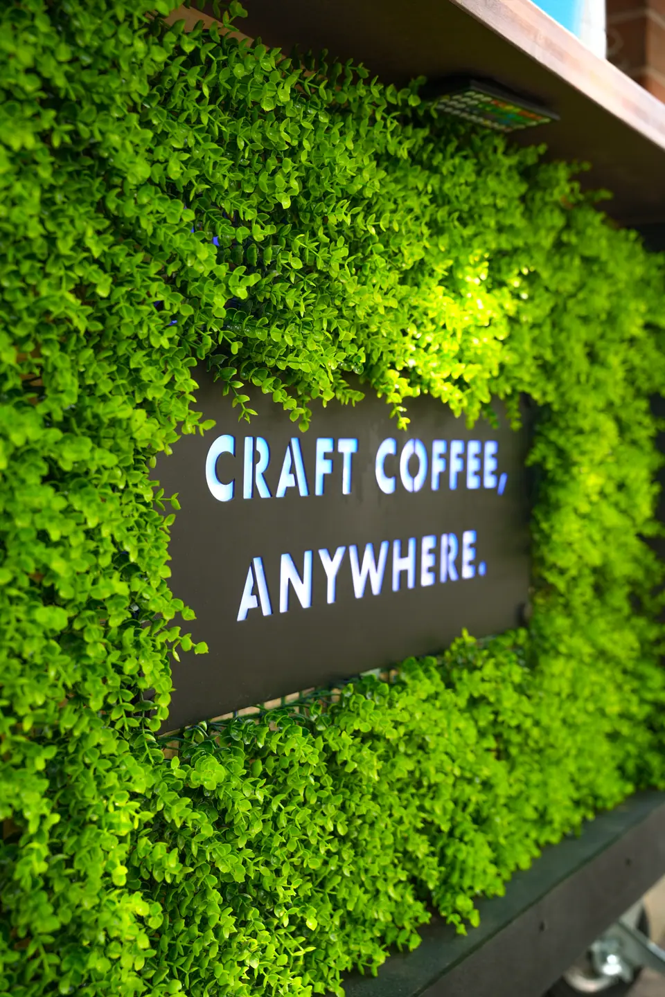 A reception venue feature wall covered in fresh greenery