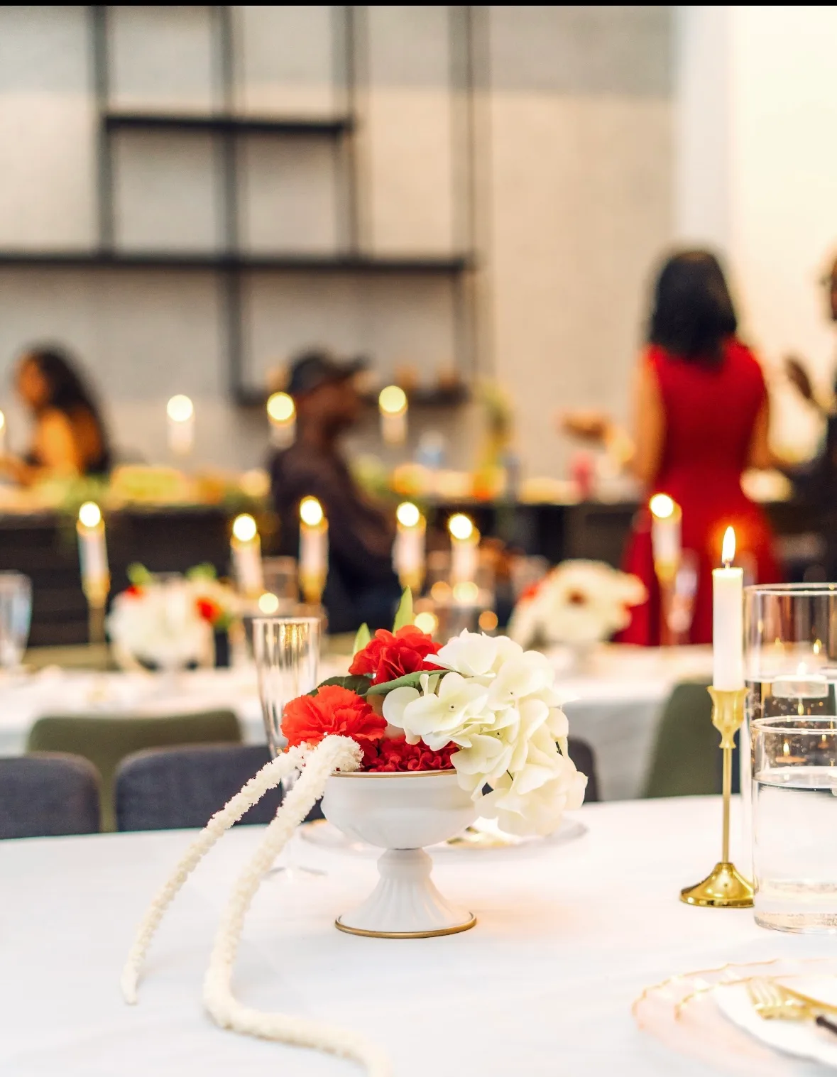 A candlelit dinner table dressed in white with red floral details