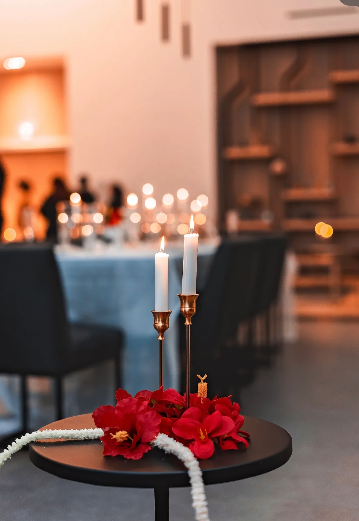 Two gold taper candle holders surrounded by red floral accents
